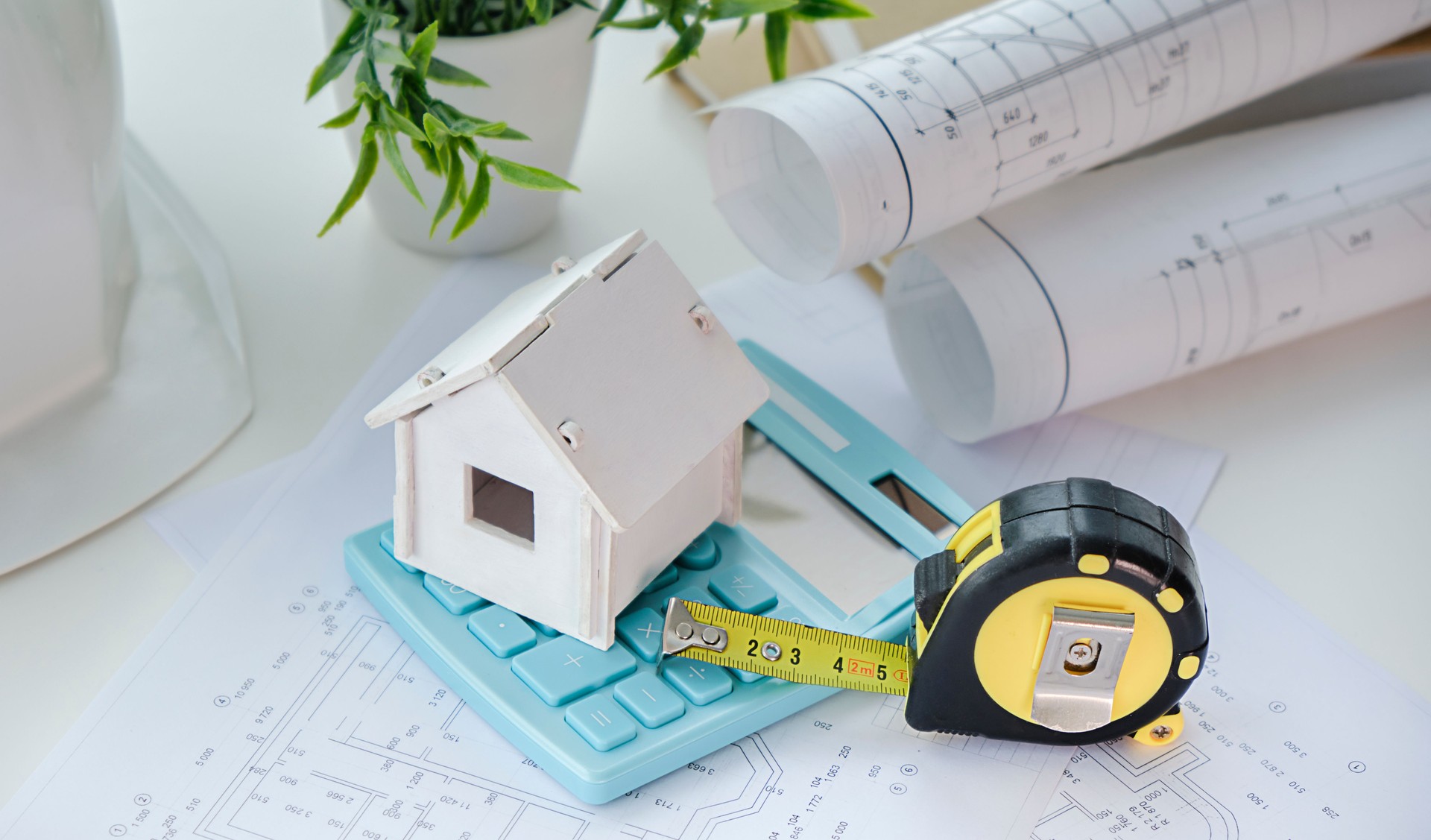 Construction company. Concept - construction business. Layout of the house. Helmet. Roulette lies on the drawings. Work in a construction company. Building. Engineer's desk. Layout plan of the rooms